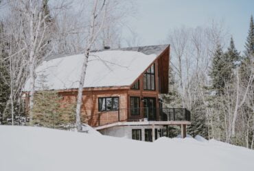 A cabin in the woods covered by snow.