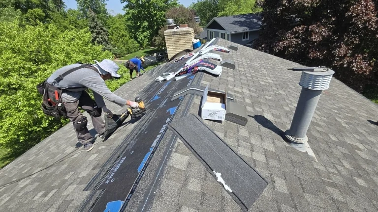 Roofer installing shingles and ridge components on a Twin Cities home