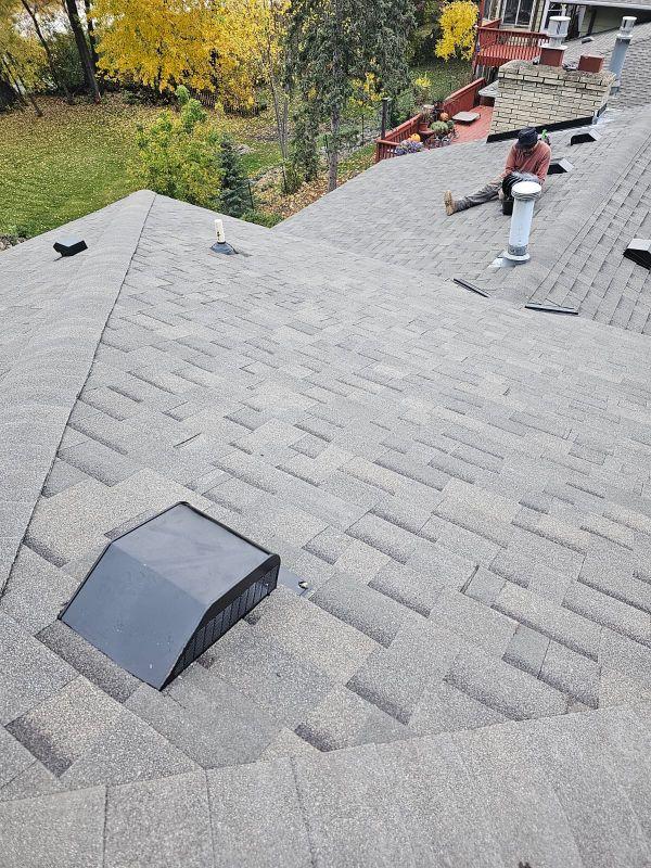 Completed architectural shingle roof replacement on a Saint Paul, MN home in autumn — black box vents and metal chimney flashing installed by Sellers Roofing