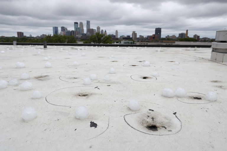 Hail-damaged commercial TPO membrane in Minneapolis, MN with adjuster chalk circles marking impacts