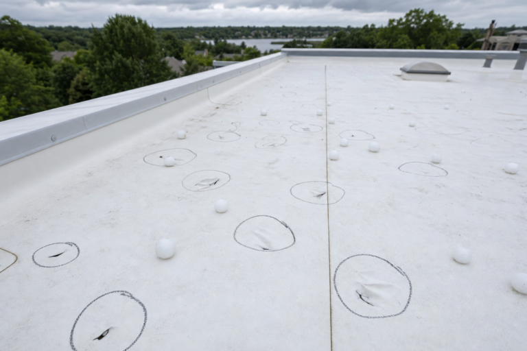 Hail-damaged commercial TPO membrane in Shoreview, MN with adjuster chalk circles marking impacts