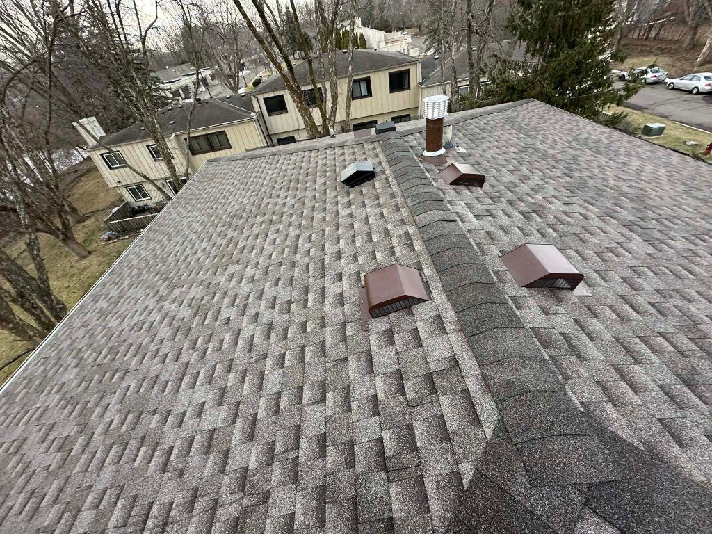Completed residential architectural shingle roof installation with ridge vents and chimney cap by Sellers Roofing — Twin Cities, MN