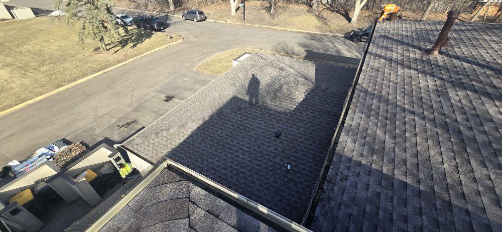 Residential dark-charcoal architectural shingle roof replacement in progress in Saint Paul, MN — Sellers Roofing union crew with on-site dumpster and material staging